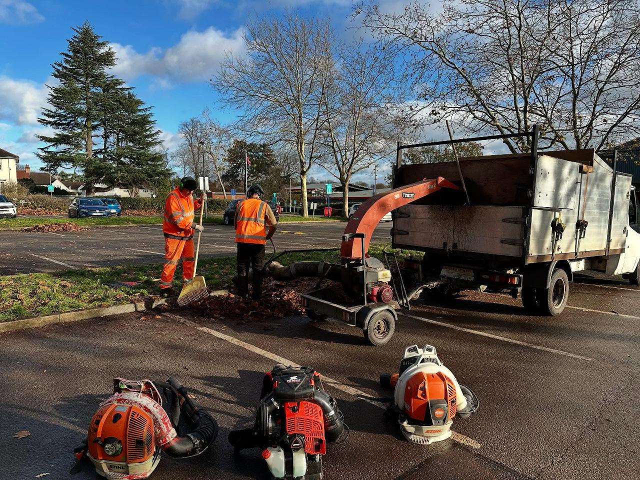 Grounds team clearing leaves with a wood chipper and blowers